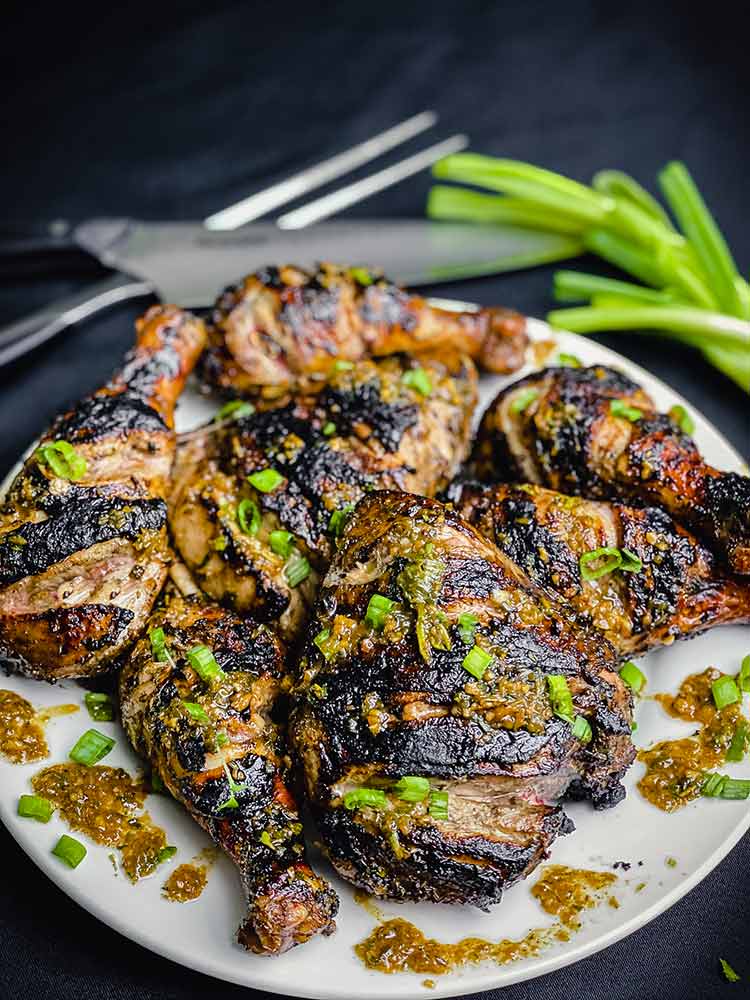 Imagine a plate filled with tender, grilled chicken that’s been marinated in a mix of allspice, cloves, cinnamon, scotch bonnet peppers, and a hint of sweetness