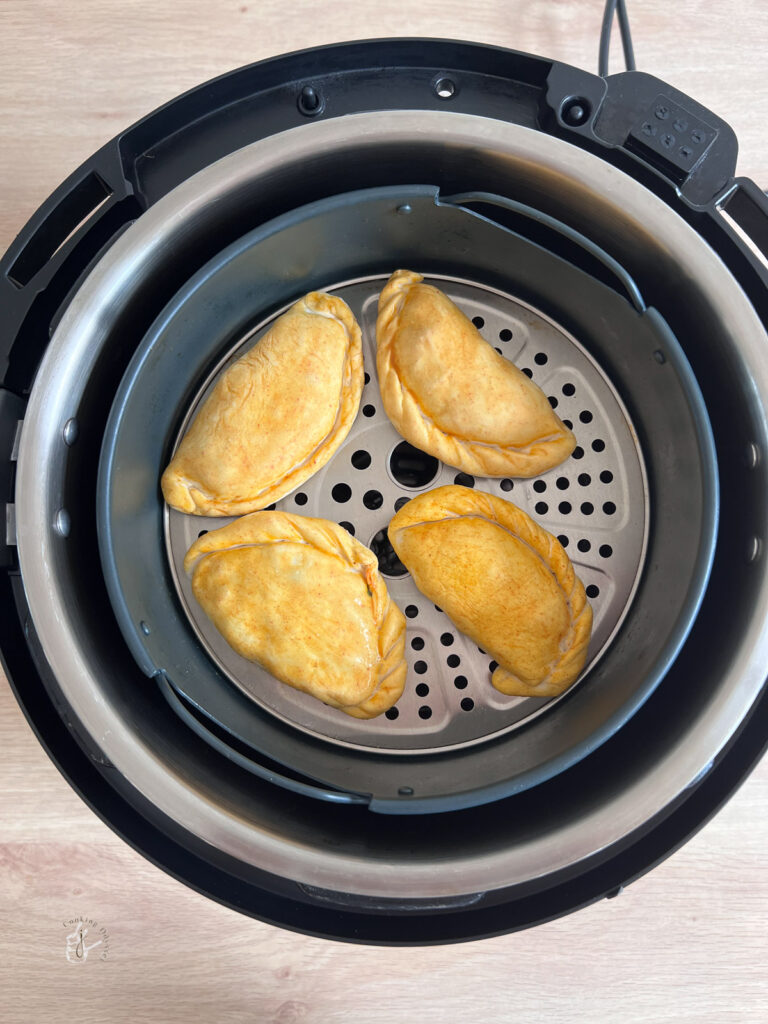 Golden empanadas inside an air fryer for crisp reheating.