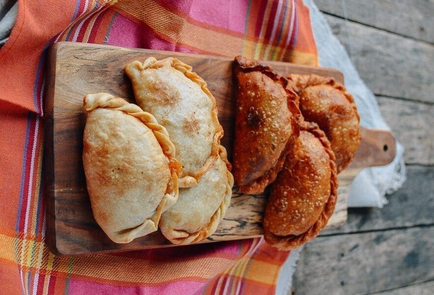 Comparison of baked and fried empanadas on cutting boards.