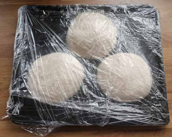 Homemade empanada dough balls individually wrapped and ready for freezing.