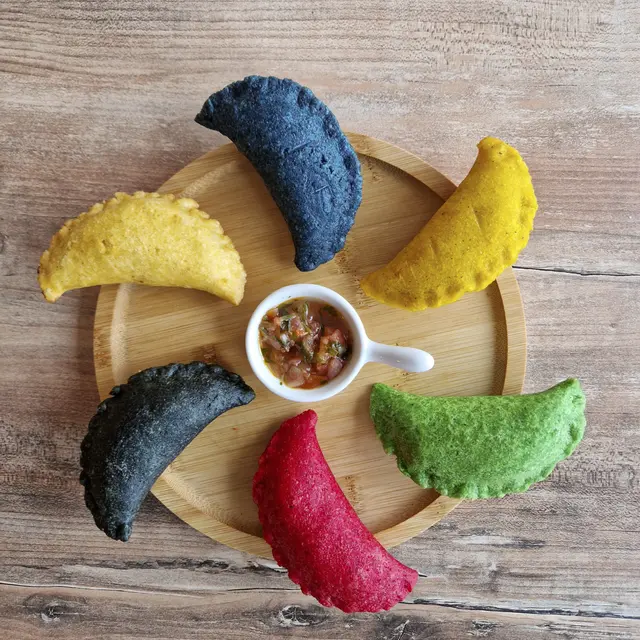 Rows of colorful empanadas made with natural vegetable-dyed dough.
