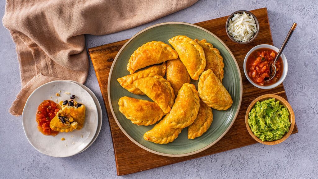 Make-your-own empanada meal kit laid out with dough rounds, filling tubs, and dipping sauces.