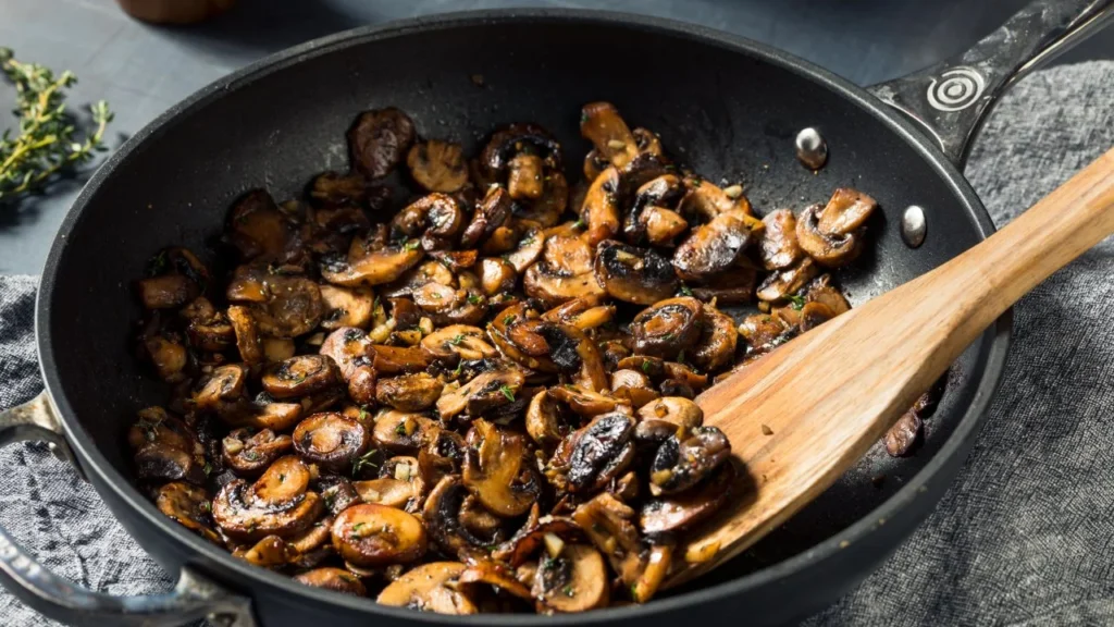 Mushrooms and vegan cheese sautéed together in a pan, ready for use as an empanada filling.