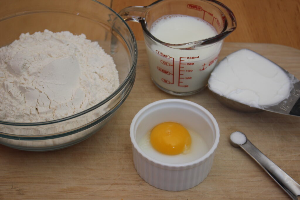 All-purpose flour being measured and mixed into empanada dough.